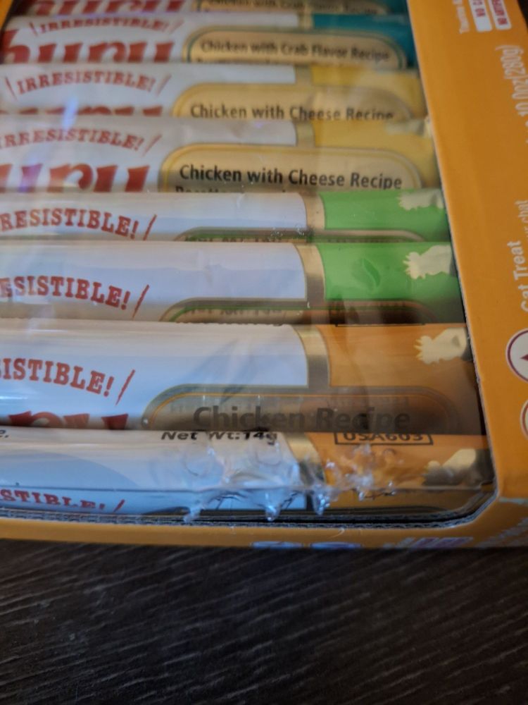 Lickable kitty treat box with a visible cat bite in the plastic