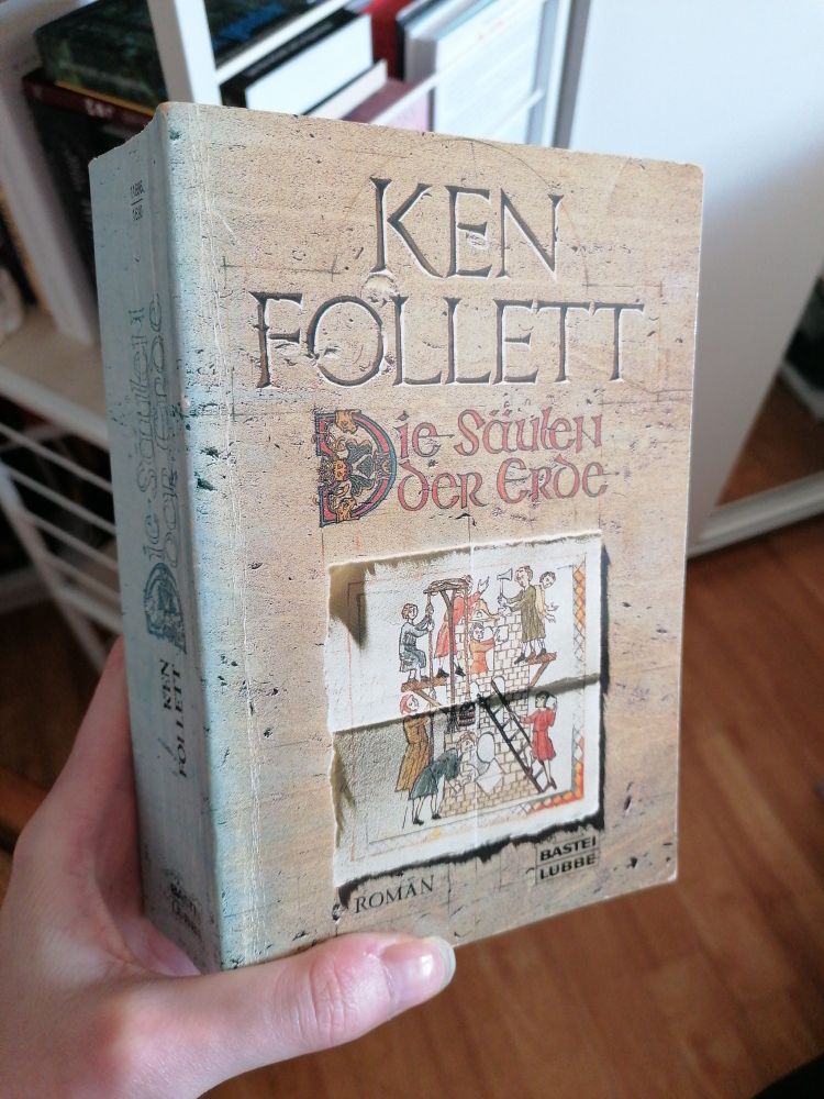 Eine sehr alte taschenbuchausgabe von die Säulen der Erde mit dem Titel in nachgemachter mittelalter Schrift und einem zu blau verblichenen Buchrücken. 