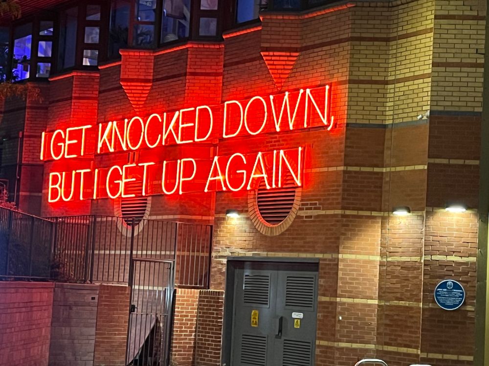 Neon text that says I get knocked down but I get up again. On the side of the West Yorkshire Playhouse in Leeds. 