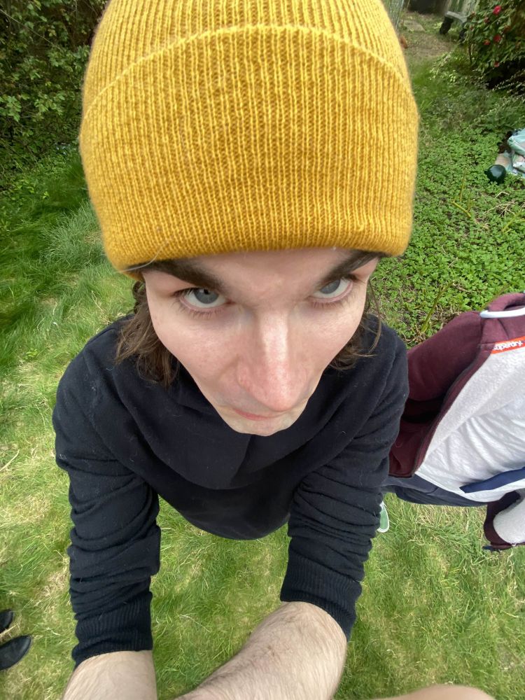 A photo of Jacob C. Rose taken from a "top view" position, resulting in a rather humorous image of Jacob's face. Jacob is also wearing a yellow beanie and a black shirt.