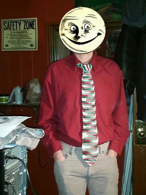 A standing person with a moon from a Sandman graphic novel for a face in a red shirt wearing a ghastly garter-stitch tie in variegated red, green, and white.  You can't tell from the picture, but I seem to recall it having metallic filaments in it, too.