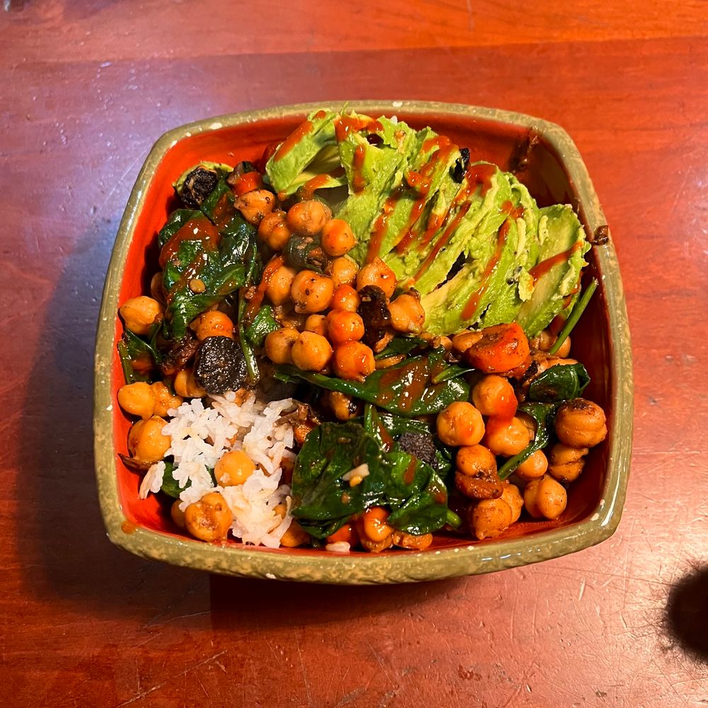 Roasted chickpeas and carrots with spinach, avocado and blue agave sriracha over rice