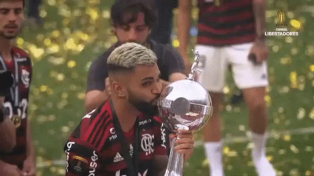 a soccer player is kissing a trophy while holding it in his hand .