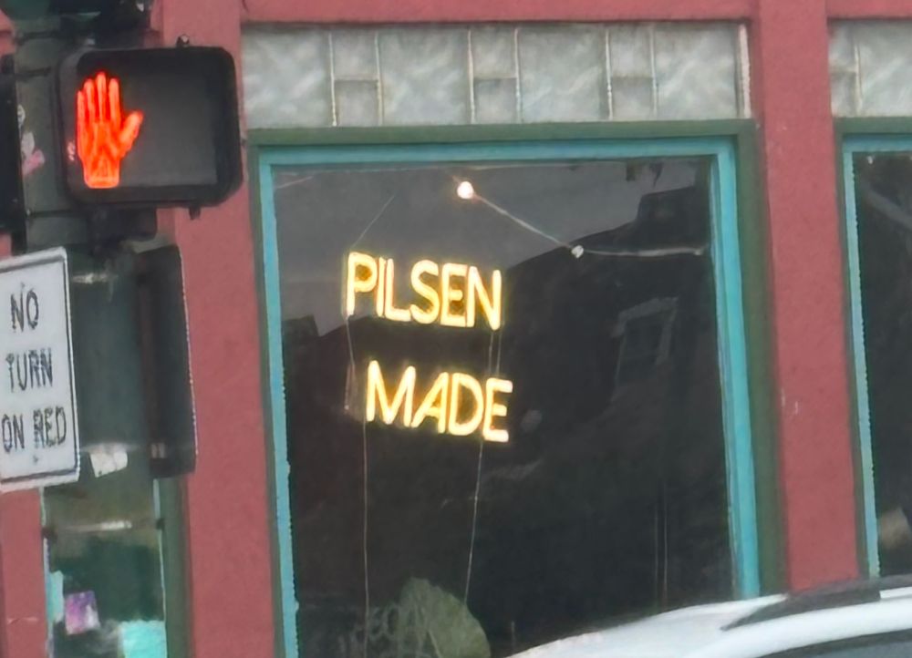 sign of a storefront with a neon sign saying "pilsen made"