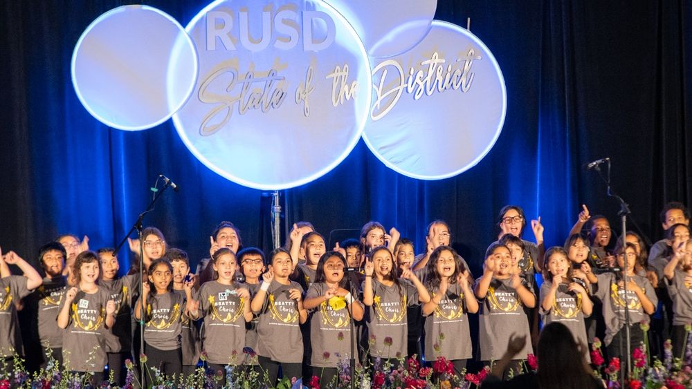 A photo of students singing on stage at the RUSD State of the District event.