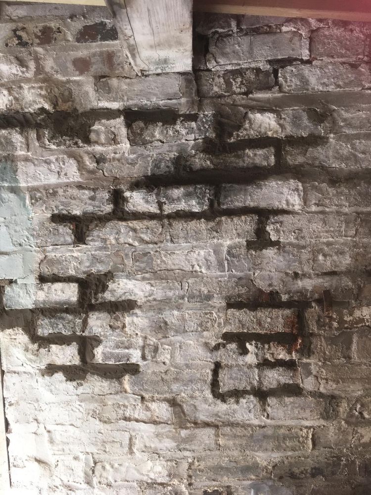 A battered old brick wall, made up of whitewashed, battered old bricks. 
