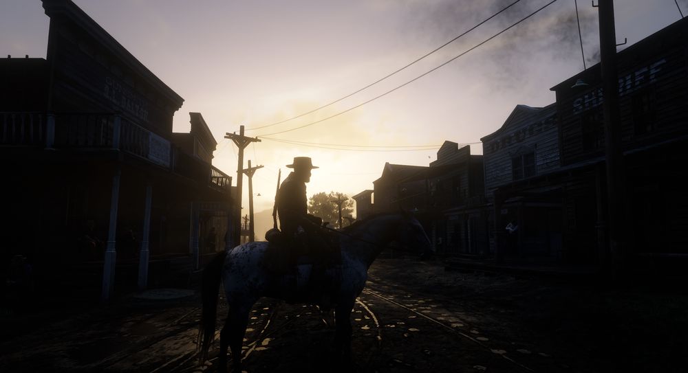 A man riding a horse through a muddy town during sunset. Warm colors are illuminating the buildings and sky behind him.