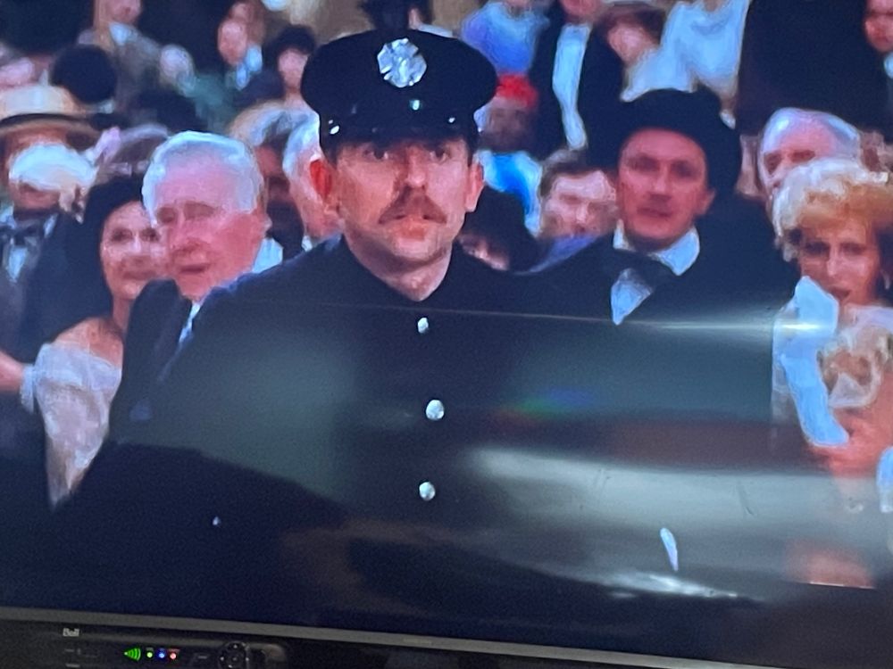 John Ratzenberger playing a cop in Ragtime (1981), a year before he started featuring as Cliff Clavin on the TV sitcom Cheers (1982-1993).