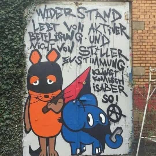 Ein Graffiti mit den der Maus dem Elefanten. Bei sind vermummt Die Maus die Flagge der Anarchisten in der Hand der Elefant eine Spraydose im Rüssel zu lesen ist Widerstand lebt von aktiver Beteiligung und nicht von stiller zustimmung klinglt komisch ist aber so