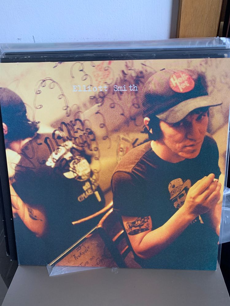 Album cover, smith wearing a peaked har with cigarette in hand sitting in front of a doofled on mirror 