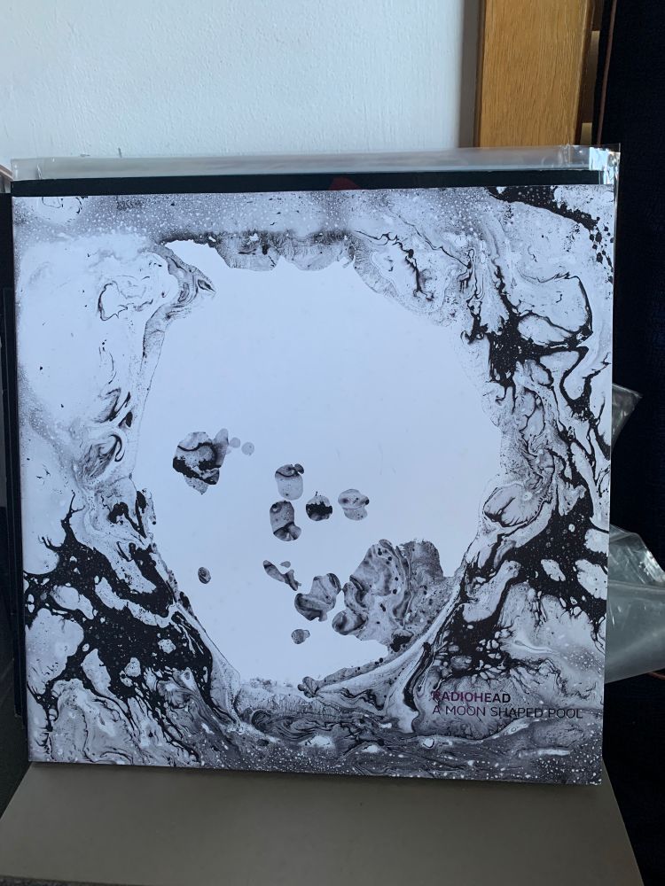 Album cover, white background with liquid type formations circling the centre 