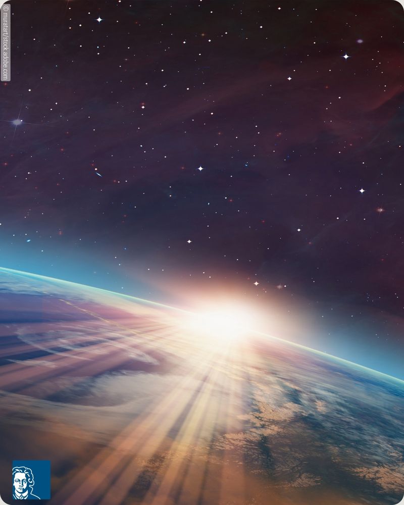 View of Earth from space during sunrise, with sunlight casting long rays across the planet's surface and atmosphere; a star-filled sky with nebulae visible in the background.