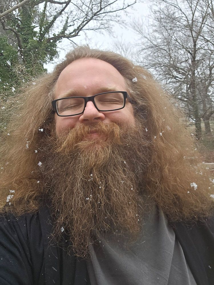 Snarky stands there smiling, eyes closed, as the first snowfall of the year begins around him. 