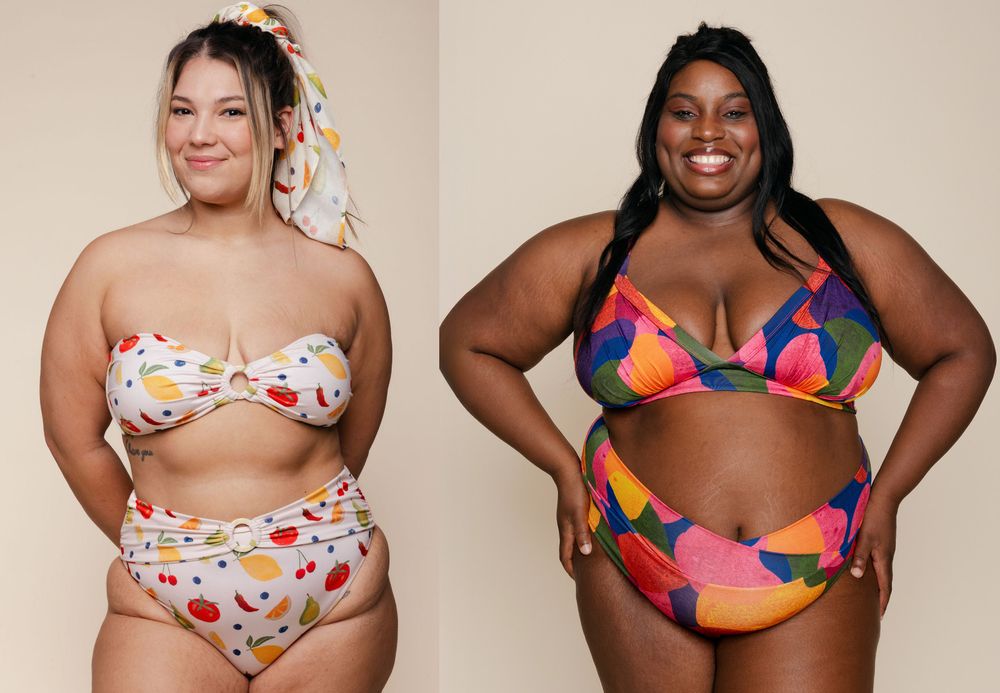Two women standing next to each other wearing plus-sized bikinis. The one on the left is wearing a white, eccentric, fruit-patterned one, and the woman on the left is wearing a colorful, abstract, floral-print one.