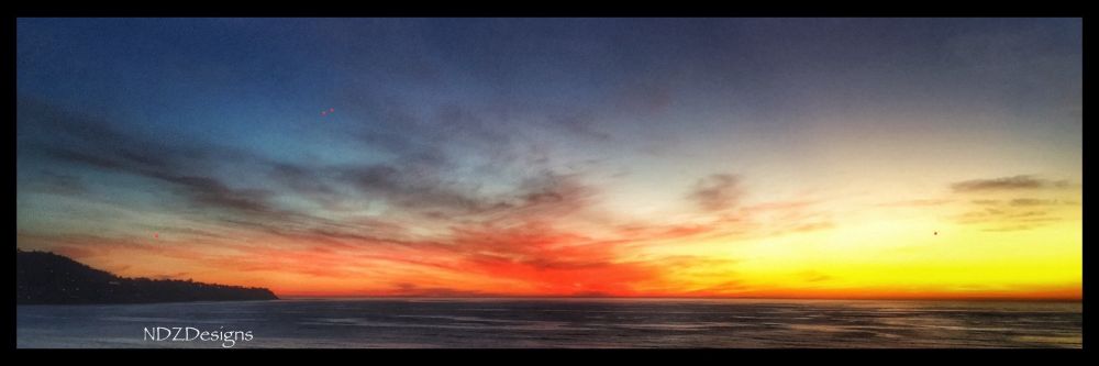 Photo taken in autumn 2018 of the sun setting over the pacific towards Catalina in various colors of orange, red, and yellow 
