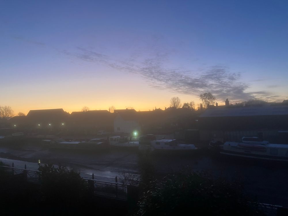 Band of pinkish light behind the buildings across the creek