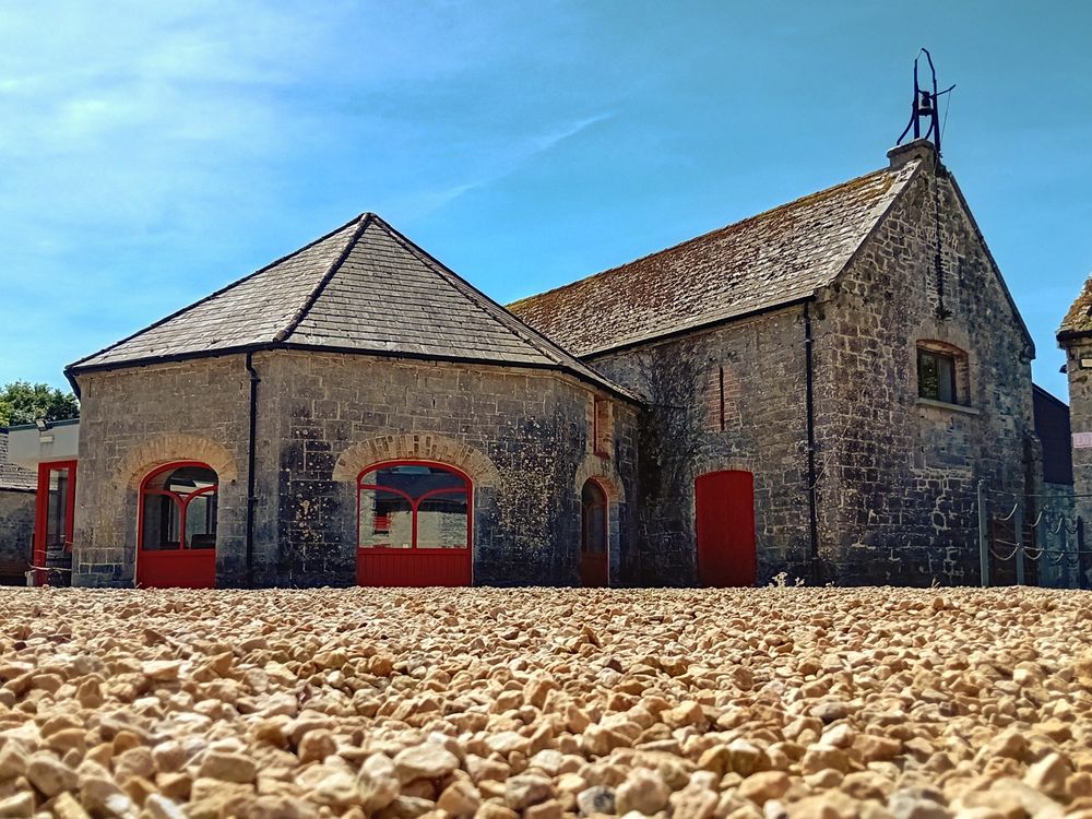 Bright blue sky above old stone buildings, with slate roofs and red doors