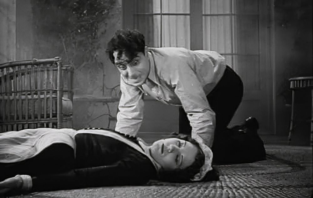 A crazed man crawls over on all fours towards a maid in a supine position on the floor.