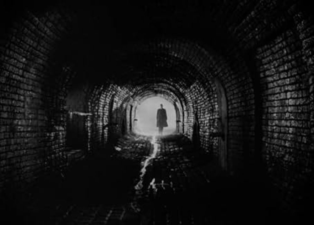 The underground foot chase scene from THE THIRD MAN (1949) depicting different silhouettes and shadows moving in underground tunnels.