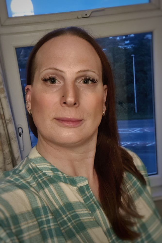 Red headed long haired woman wearing a blue/green plaid top