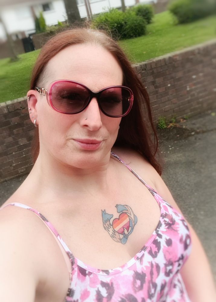 Red headed long haired woman wearing a pink top