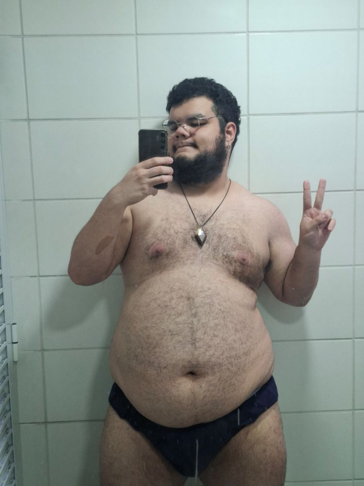 foto minha (homem branco, gordo, peludo, de cabelo e barba pretos, óculos redondo) só de cueca slip preta no espelho de um banheiro. estou fazendo o sinal de paz e amor com a mão direita e segurando o celular com a esquerda