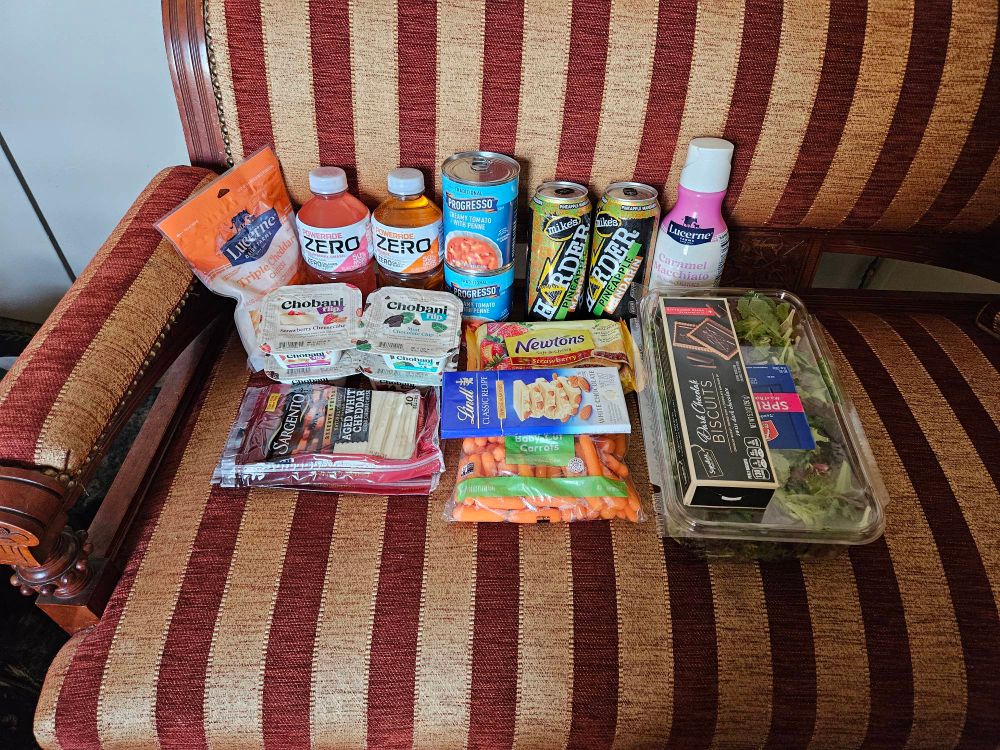 19 items from the grocery store sit in a red and gold vertically striped piece of furniture. 