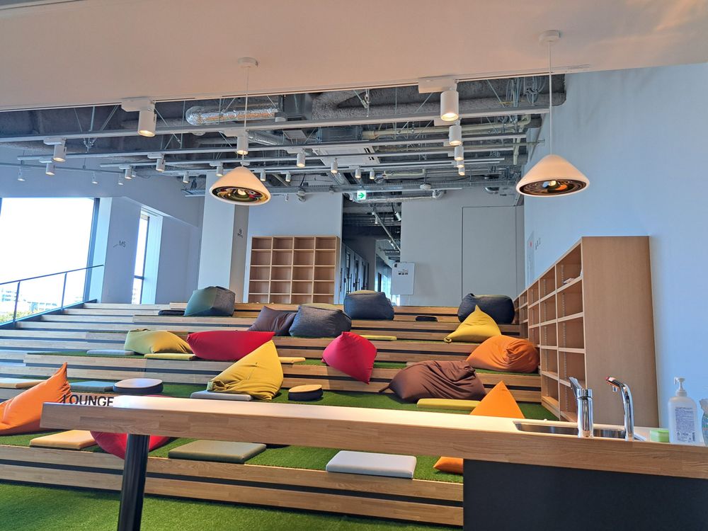 階段型ラウンジ、人工芝にクッションが散乱している。