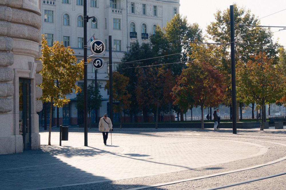 An elderly man with a walking stick on a bright street outside the Hungarian parliament