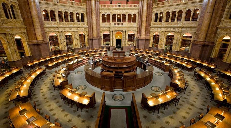 The Main Reading Room of the Library of Congress, a palatial Beaux-Arts temple to study, filled with marble columns and fine statuary, and lighted research areas arranged around a central information desk of carved mahogany