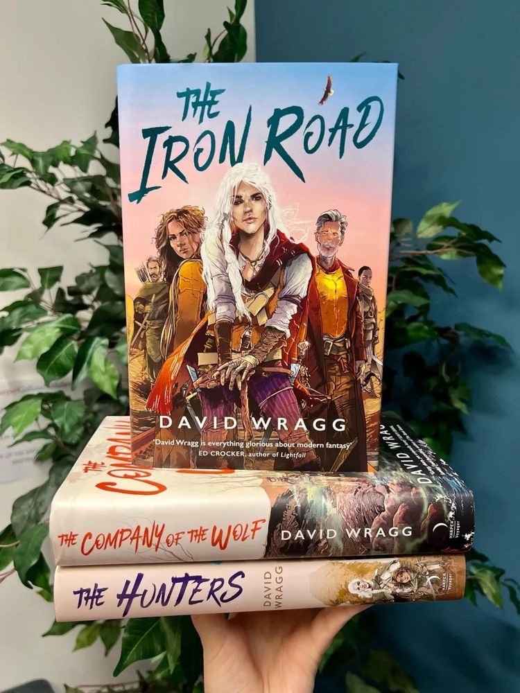 The glorious royal hardbacks of all 3 Tales of the Plains books, with The Iron Road uppermost, balanced in the hand of the person keeping the roof on
