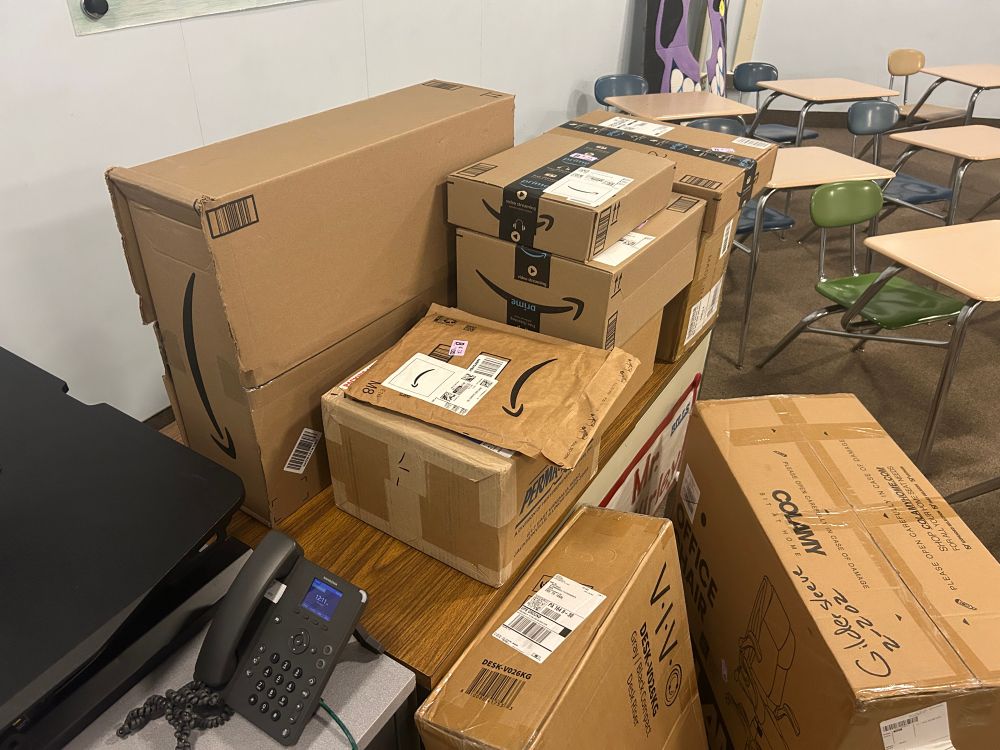 Stack of cardboard boxes of various sizes in a classroom.