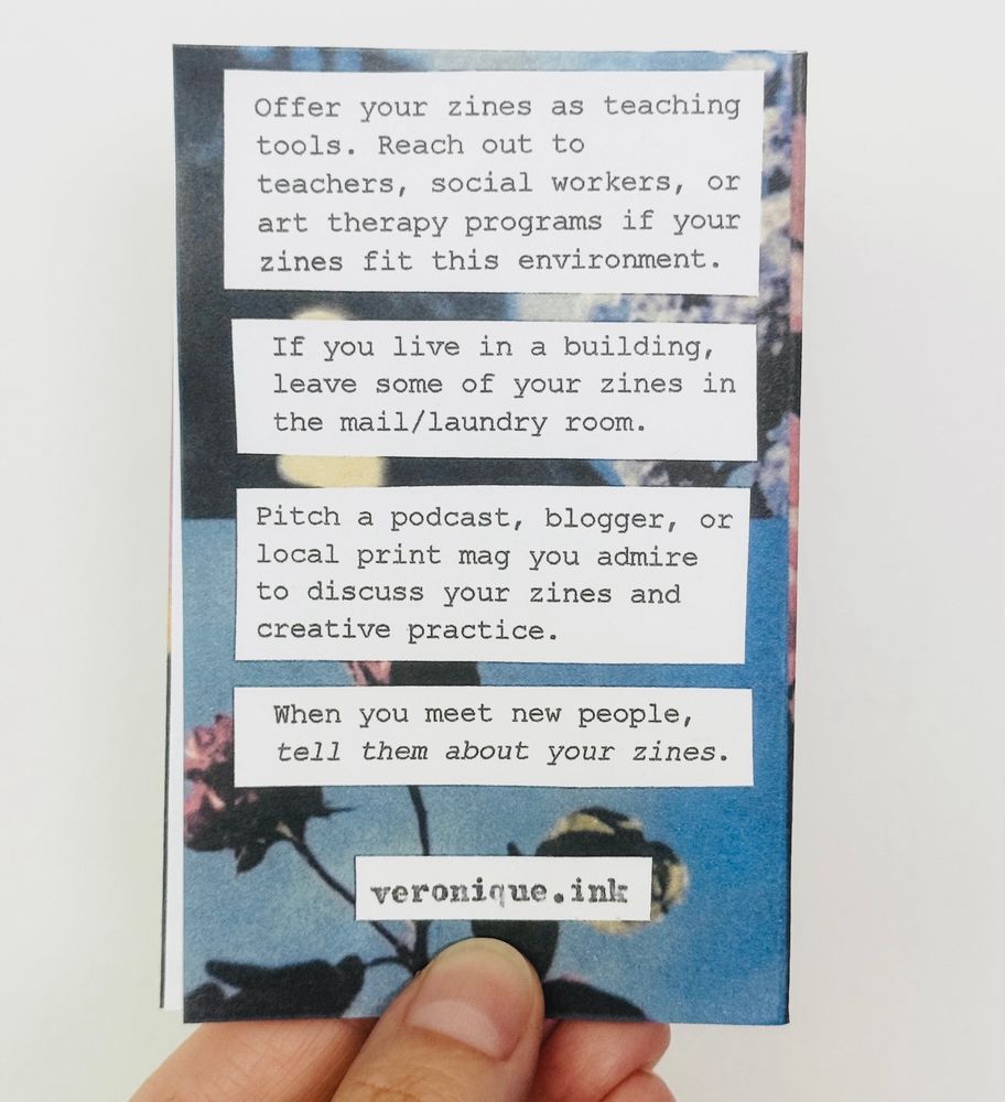 a hand holding up a zine