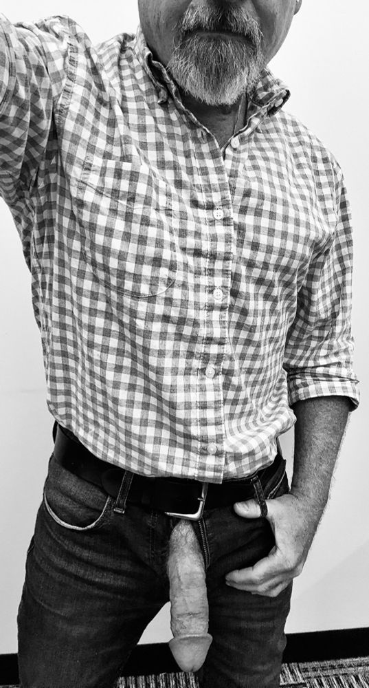 Black and white image of a Dad with his soft fat cock hanging out the fly of his jeans.  