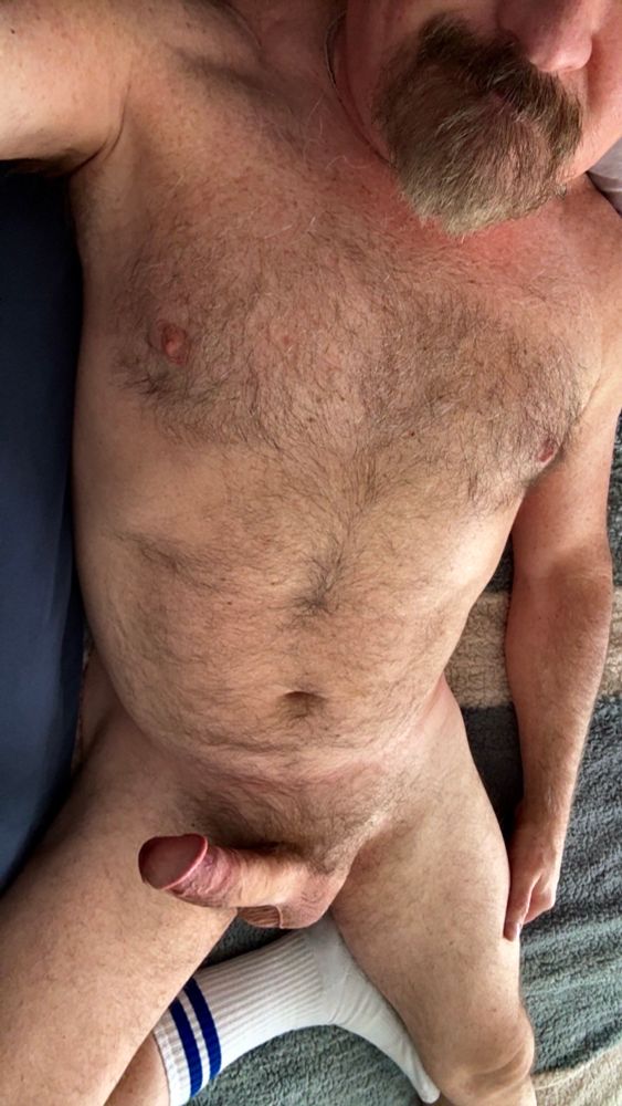 Furry naked Dad laying in bed wearing only athletic socks and getting ready for a nap, hard fat cock visible. 
