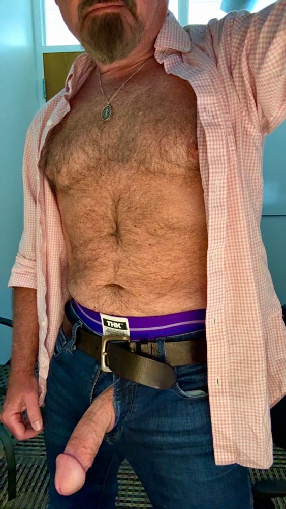 Dad in the office, pink shirt unbuttoned, purple jock waistband visible over unzipped jeans, thick cock hanging out the fly. 