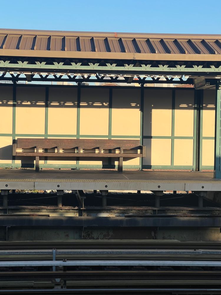 Picture of the subway station, outside, featuring a bench.