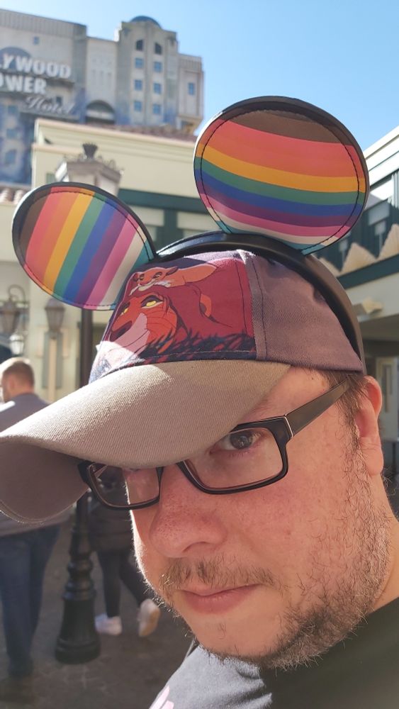A nerd in disneyland Paris wearing a lion King hat and pride ears