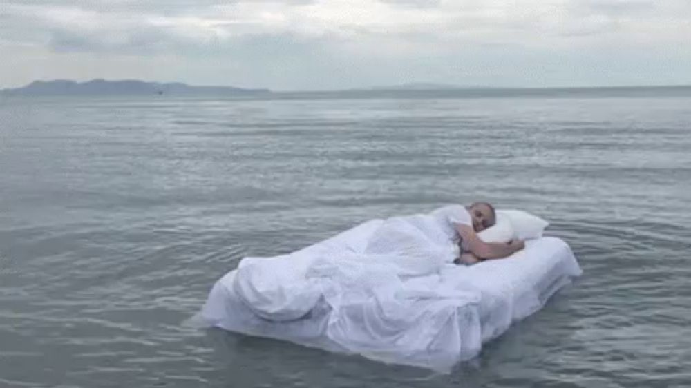 a man is sleeping on a mattress in the middle of the ocean .