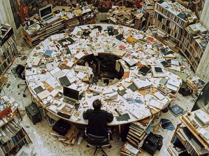 A PhD student sitting behind a round table with too many materials to review