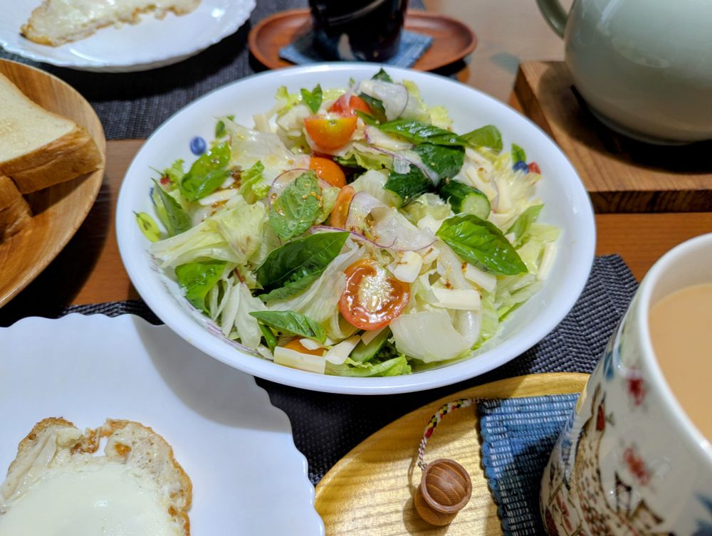 レタス、叩ききゅうり、ミニトマト、バジル、紫たまねぎ、チーズのサラダ、トースト、ミルクティー、目玉焼きの朝ごはん。