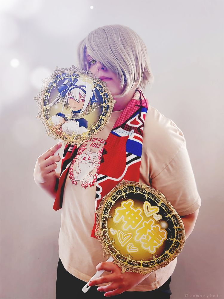 Forte cosplay pic in the Meakyu version of the Tales of Festival 2023 shirt. Featuring a Meakyu neck towel, and most importantly, two Kasque oshi uchiwa fans. The fan featuring Kasque's reference art is held up to my face, partially obscuring it, while the one reading 神様 is held lower.