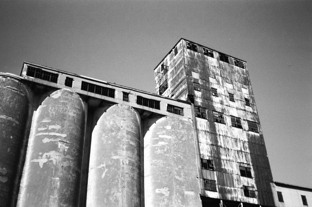 black & white: cylindrical cement silos as part of a dilapidated building that extends over them