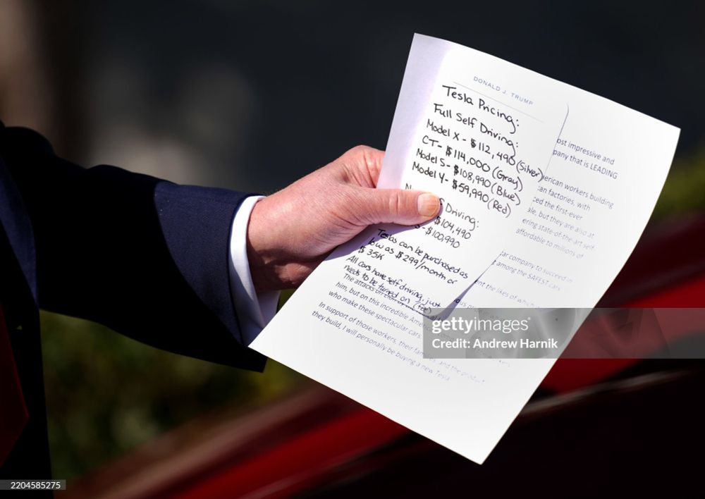 A comically small hand poking out of an ill fitting blue suit clammily clings to a couple papers, the top of which lists Tesla colors, options, and prices as well as financing info and talking points. Essentially everything a car sales associate—or in this case, the President of the United States of America—would need to try to hawk some electric cars. 