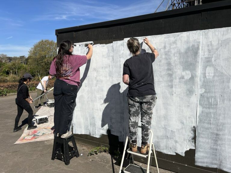 Volunteers painting the hoardings around the remains of Broomfield House