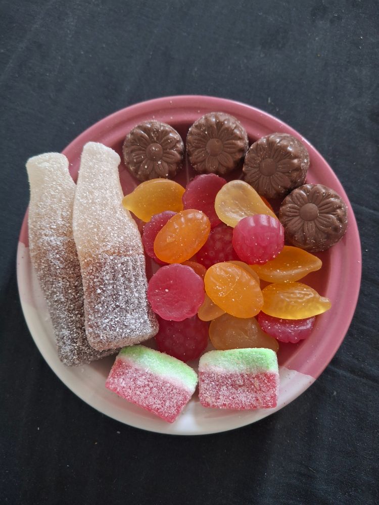 Irtokarkkeja lautasella: toisella reunalla muutamia kirpeitä karkkeja, toisella suklaita ja niitten välissä perus tuttifruttikarkkeja.