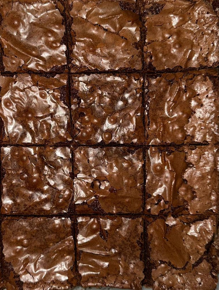 foto em close de um brownie de chocolate. uma indecente foto da casquinha brilhante e quebradiça que revela um doce suculento e macio