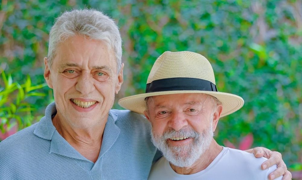 Foto de Lula e Chico Buarque. Os velhos estão sorridentes e abraçados de lado, em frente a um muro vivo. Lula está vivo e viçoso, enquanto a edição da foto deixou Chico sem vida, a cara pálida, sem um sinal de estar recebendo sangue.
