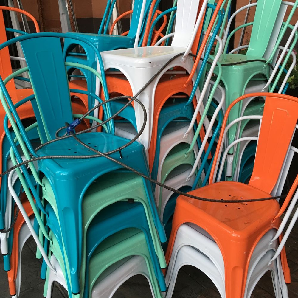Stacks of brightly colored metal cafe chairs, with a security cable laced through them,  fill the view.