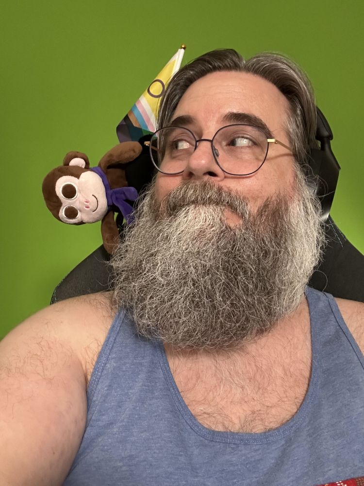 Me in a blue tank top looking over at brown plush Chair Monkey flopping down from the back of the chair above my shoulder